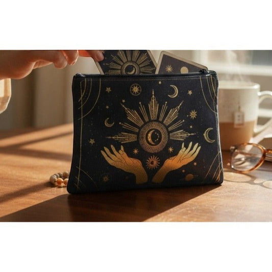 The Witches' Quest black canvas zipper pouch with gold celestial sun and moon hands design holding tarot cards.