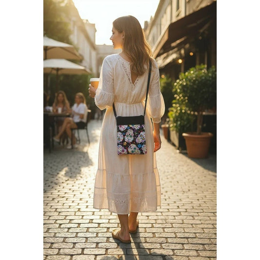 The Witches' Quest handcrafted crossbody bag with a vibrant sugar skull print worn by a woman in a white dress.