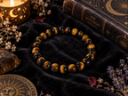 Natural Tiger Eye crystal 8mm stretch bracelet on black velvet with a book and candle