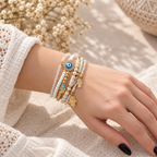 Evil Eye and Hamsa layered bracelet set with white beads and gold accents on a wrist