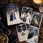 Seasons of the Witch Winter Tarot deck box and four illustrated cards on a wooden table with a candle