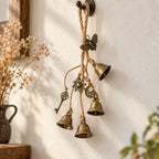 Brass-tone witch bells hanging on a wall with sun moon key and moth charms