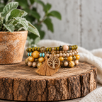 Boho tree of life beaded bracelet set with earth tone beads and a gold tassel charm on a wooden log slice