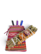 The Witches' Quest altar kit featuring a colorful woven bag, three ritual candles, and a rosemary and cinnamon bundle.