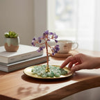 The Witches' Quest amethyst gemstone tree with wire branches on a gold tray with green aventurine chips on a desk.