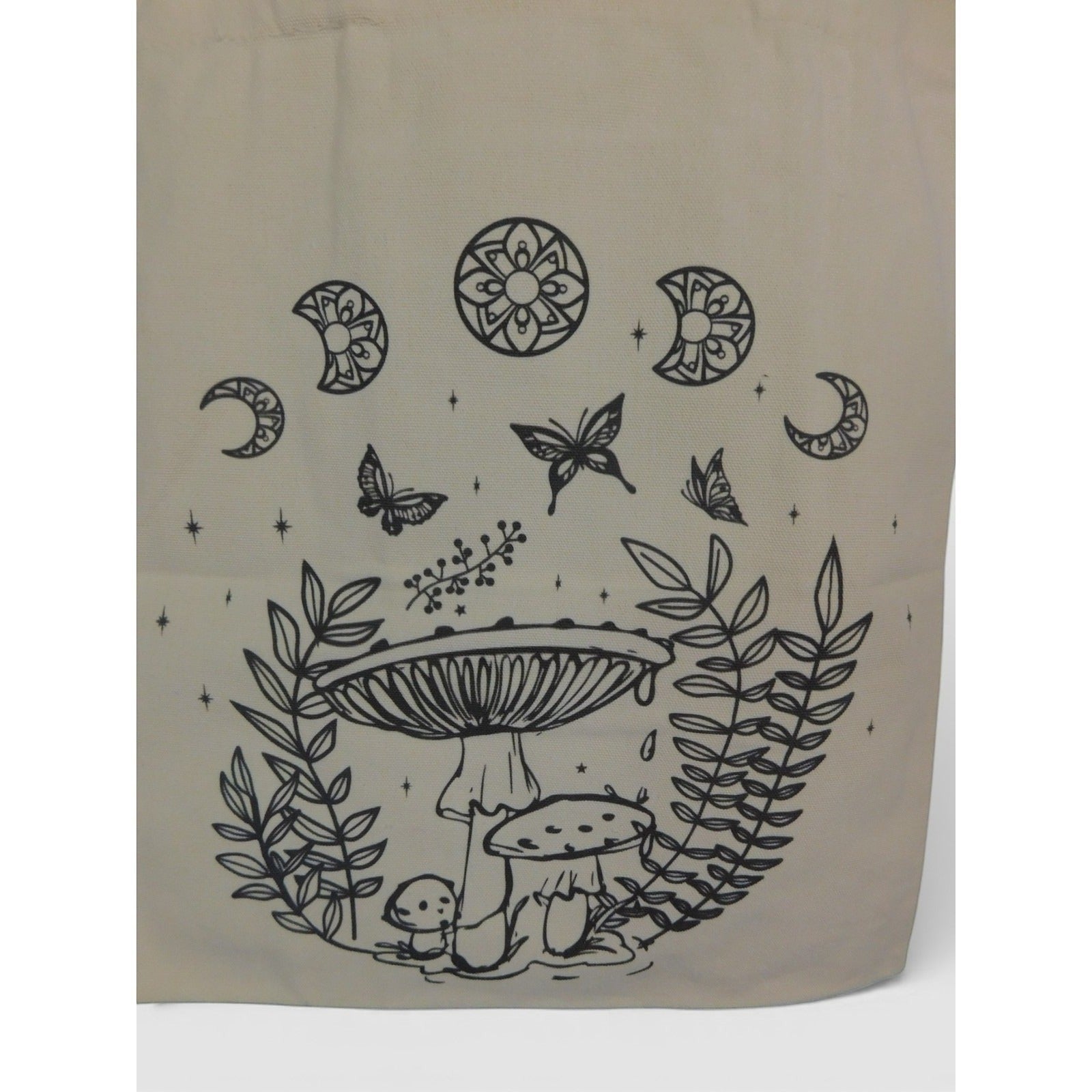 The Witches' Quest beige canvas tote bag featuring black line-art of mushrooms, butterflies, and celestial moon motifs.