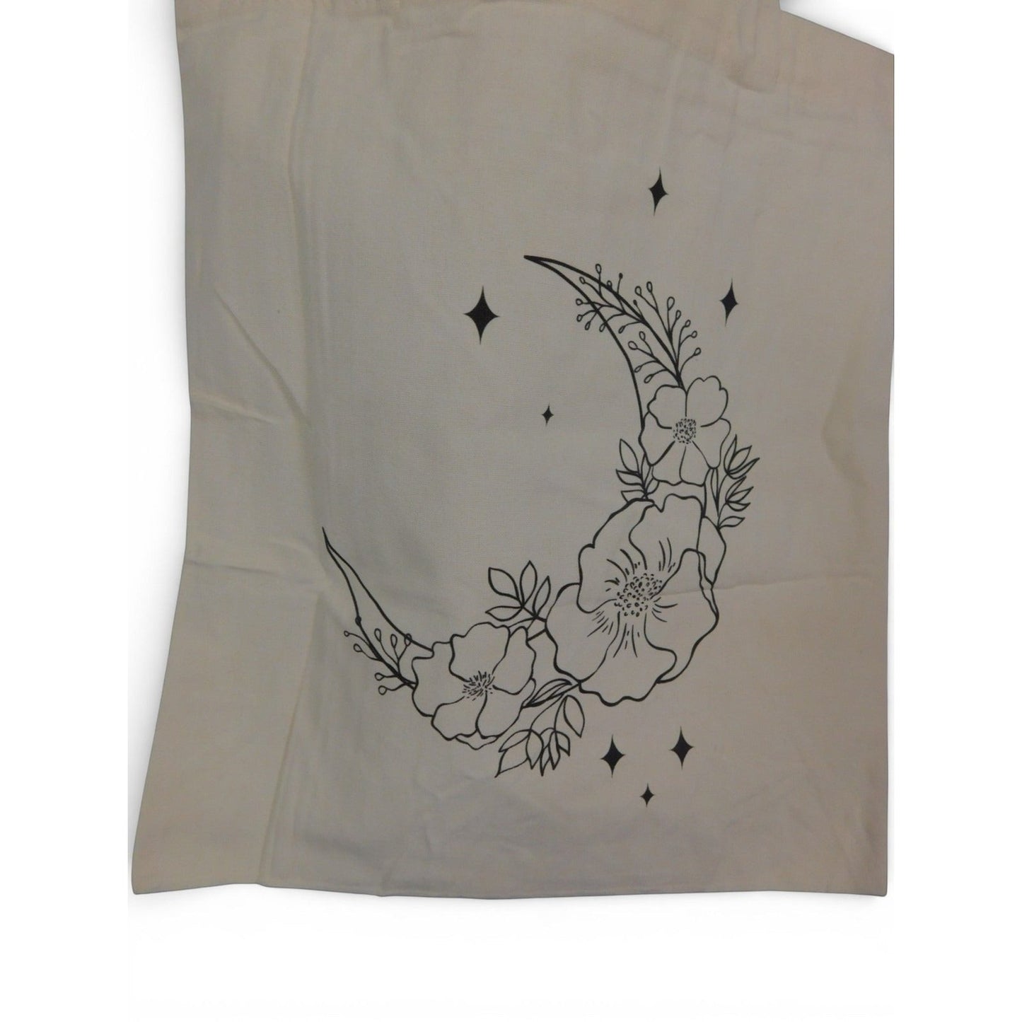 The Witches' Quest beige canvas tote bag featuring a black line art crescent moon, floral, and star print.