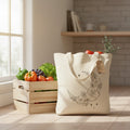 The Witches' Quest beige canvas tote bag featuring a black line art crescent moon, floral, and star print.