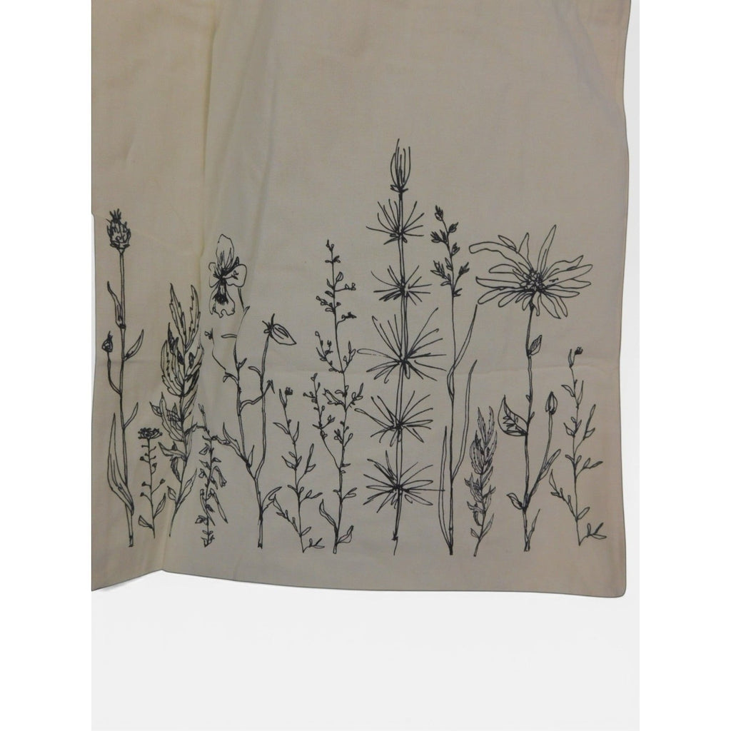 The Witches' Quest beige canvas tote bag with black wildflower line art botanical print on the front panel.