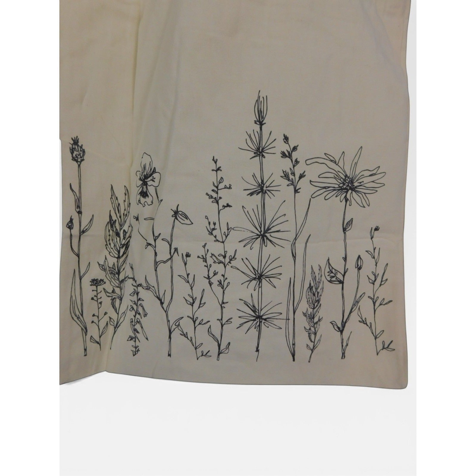 The Witches' Quest beige canvas tote bag with black wildflower line art botanical print on the front panel.