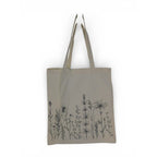 The Witches' Quest large beige cotton canvas tote bag featuring black wildflower line art illustrations on the front.