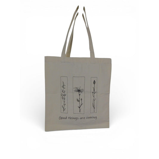 The Witches' Quest beige canvas tote bag featuring black floral line art and the quote Good things are coming