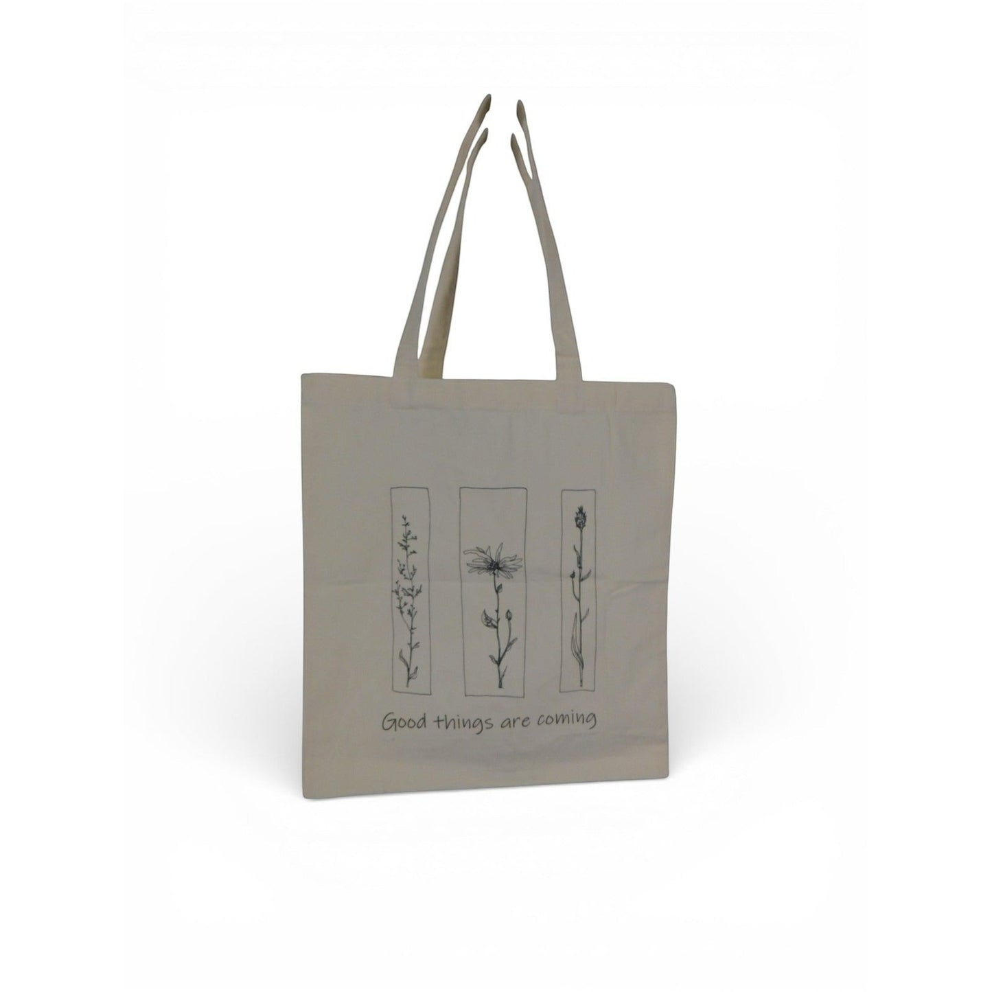 The Witches' Quest beige canvas tote bag featuring black floral line art and the quote Good things are coming