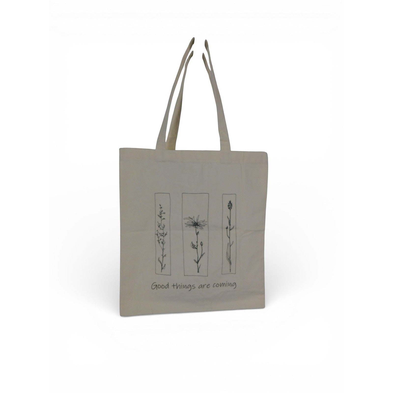 The Witches' Quest beige canvas tote bag featuring black floral line art and the quote Good things are coming