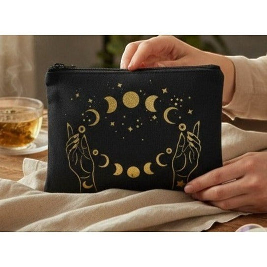 The Witches' Quest black canvas zipper pouch with gold celestial moon phase and hand print design.