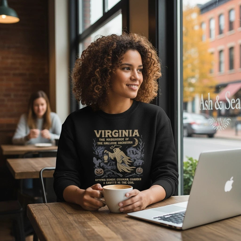 The Witches' Quest black crewneck sweatshirt with a spooky colonial ghost graphic, worn by a woman in a cafe.