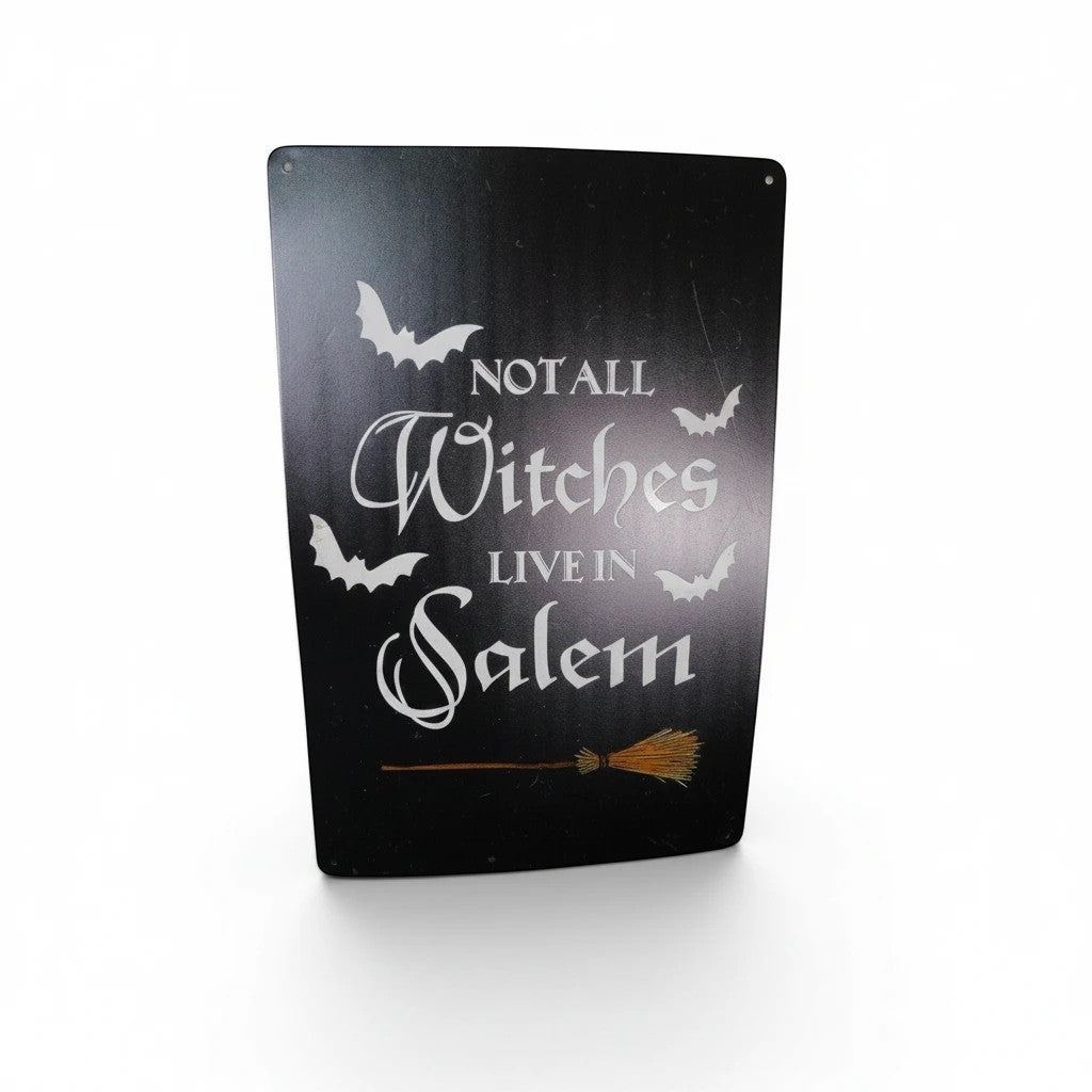 The Witches' Quest black metal wall sign with white text reading Not All Witches Live In Salem and bat graphics.