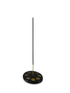 The Witches' Quest black stone ceramic incense holder with gold celestial moon phase design and a burning incense stick