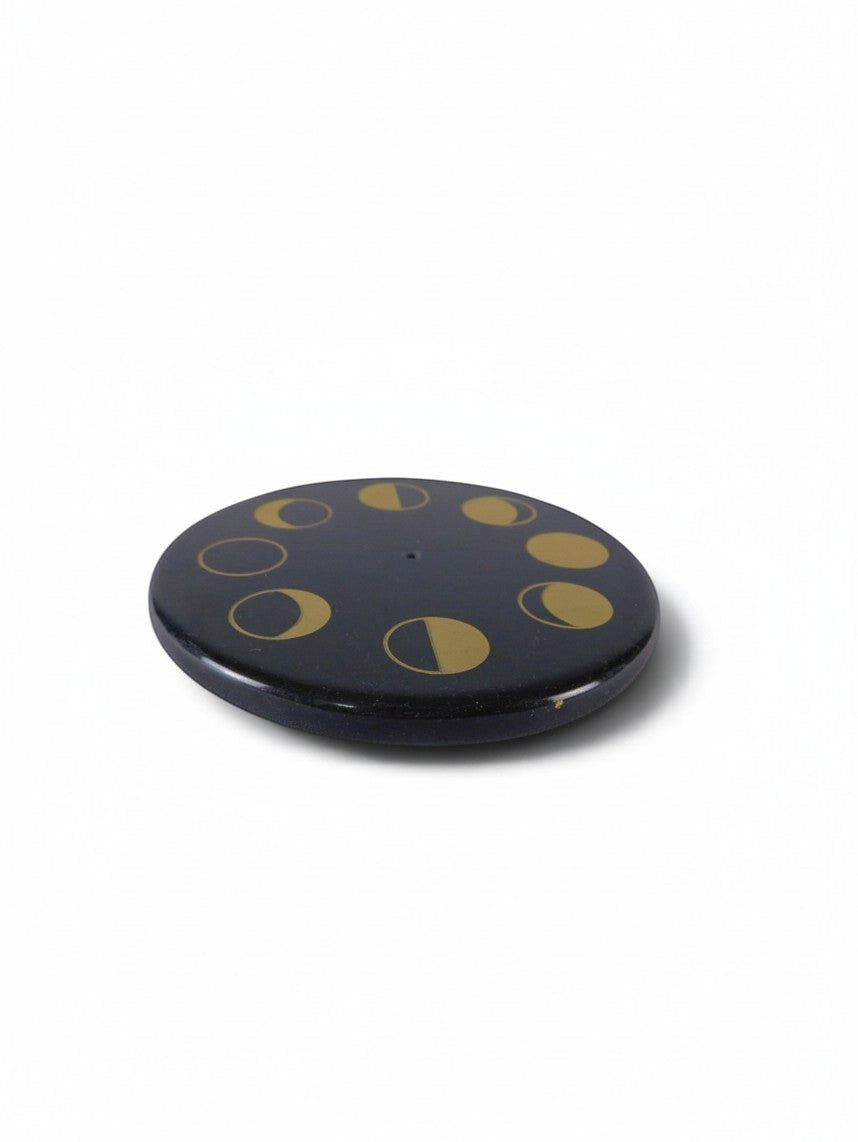 The Witches' Quest round black stone incense holder with gold celestial moon phase design and central stick hole.
