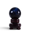 The Witches' Quest polished black obsidian scrying sphere on a dark wooden display stand against a white background.
