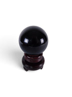 The Witches' Quest polished black obsidian sphere on a dark wooden display stand for scrying and altar decoration.