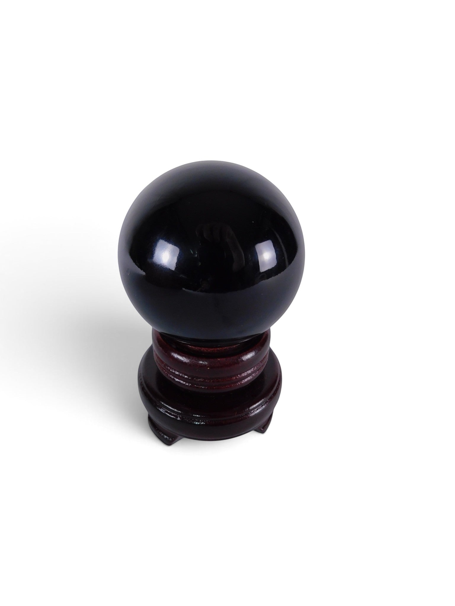 The Witches' Quest polished black obsidian sphere on a dark wooden display stand for scrying and altar decoration.