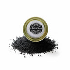 The Witches' Quest Ash & Sea black salt in a glass jar with a gold lid, used for ritual protection and cleansing.
