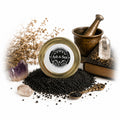 The Witches' Quest witch-forged black salt in a glass jar with crystals, mortar, and pestle for ritual protection.