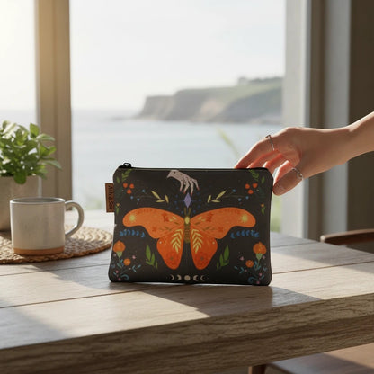 The Witches' Quest small canvas zip pouch featuring an orange butterfly, celestial moon phases, and floral motifs.