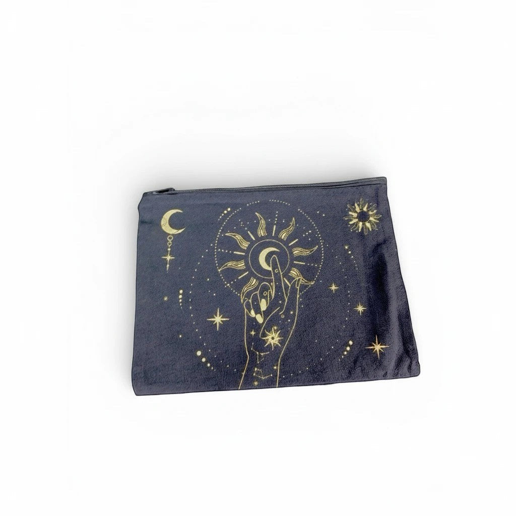 The Witches' Quest black canvas clutch featuring a gold celestial hand, moon, and sun print with a top zip closure.