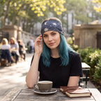 The Witches' Quest celestial moon and star print stretchy headband worn by a woman with blue hair at an outdoor cafe