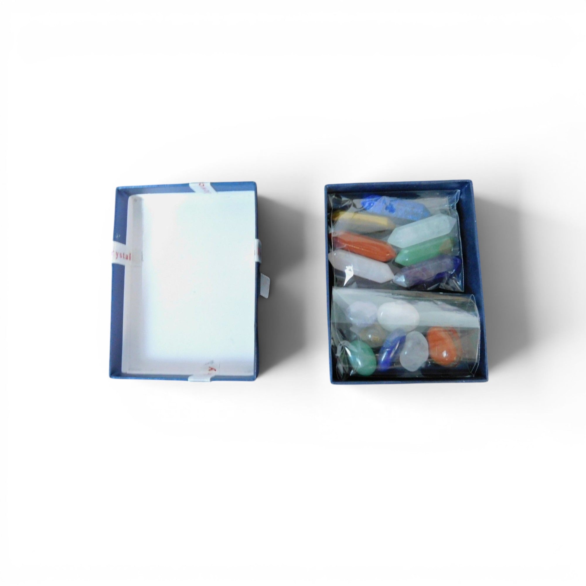 The Witches' Quest 14-piece chakra crystal set with hexagonal columns and polished stones in a blue gift box.