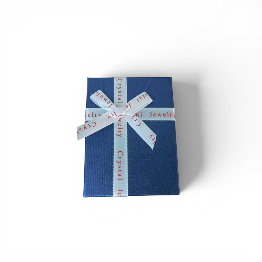 The Witches' Quest blue gift box with white ribbon containing a 14-piece chakra hexagonal crystal gemstone set.