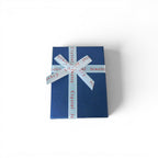 The Witches' Quest blue gift box with white ribbon containing a 14-piece chakra hexagonal crystal gemstone set.