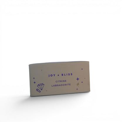 The Witches' Quest Joy + Bliss crystal set box featuring Citrine and Labradorite branding on a neutral background.