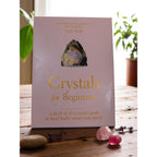 The Witches' Quest Crystals for Beginners deck of 50 instructional cards in a soft pink box on a wooden table.