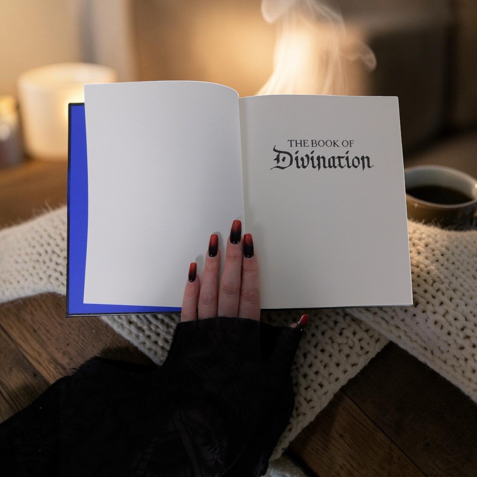 The Witches' Quest The Book of Divination hardcover guide held open with smoke rising in a cozy, mystical setting.