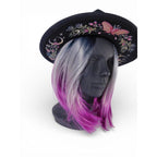 The Witches' Quest black wide brim fedora with colorful floral, moon, and butterfly embroidery on a mannequin head.