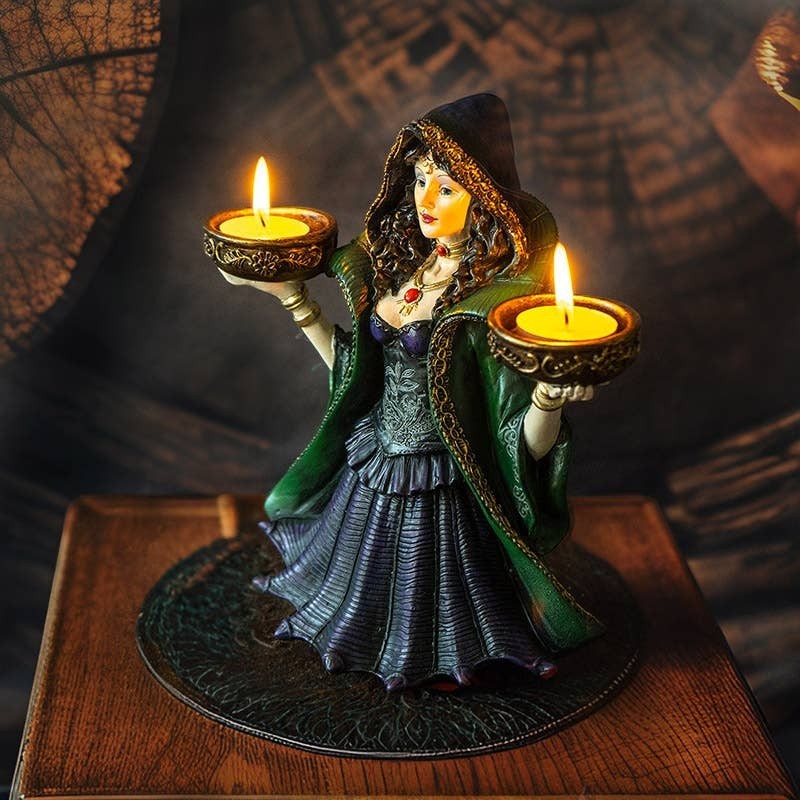 The Witches' Quest enchanted witch statue holding two tea light candles in a green and purple gown on a wooden base