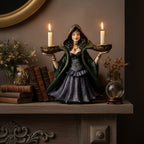 The Witches' Quest enchanted witch candle holder statue in a green and purple gown holding two lit tea light candles.