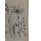 The Witches' Quest beige canvas tote bag featuring detailed black wildflower line art illustrations on the front panel.