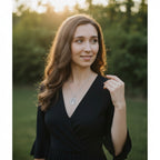 A woman wearing The Witches' Quest silver goddess tree of life pendant necklace in a soft outdoor sunset setting.
