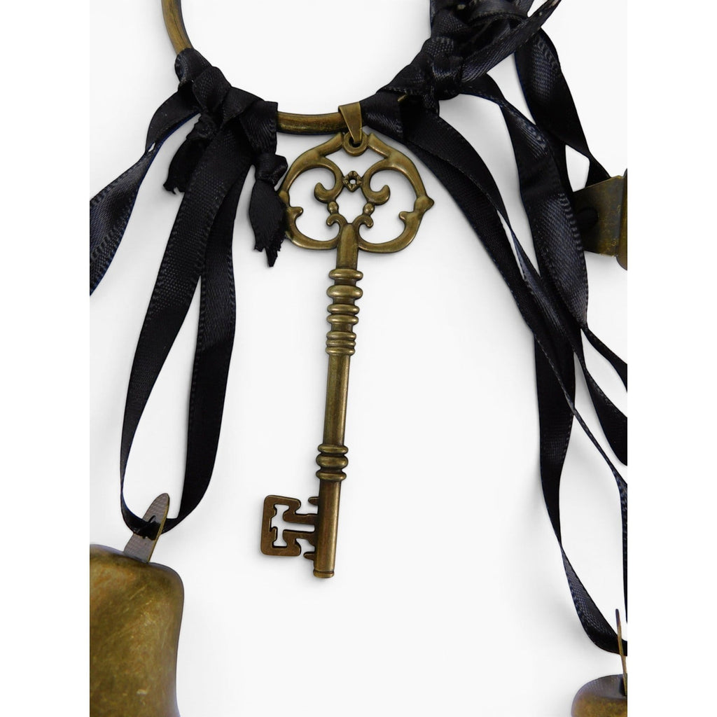 The Witches' Quest gold-tone metal skeleton key charm hanging from a circular ring with black ribbons and chime bells.