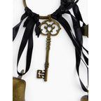 The Witches' Quest gold-tone metal skeleton key charm hanging from a circular ring with black ribbons and chime bells.