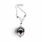 The Witches' Quest gothic bat cameo necklace in silver-tone alloy with a black resin backdrop and ornate scrollwork.