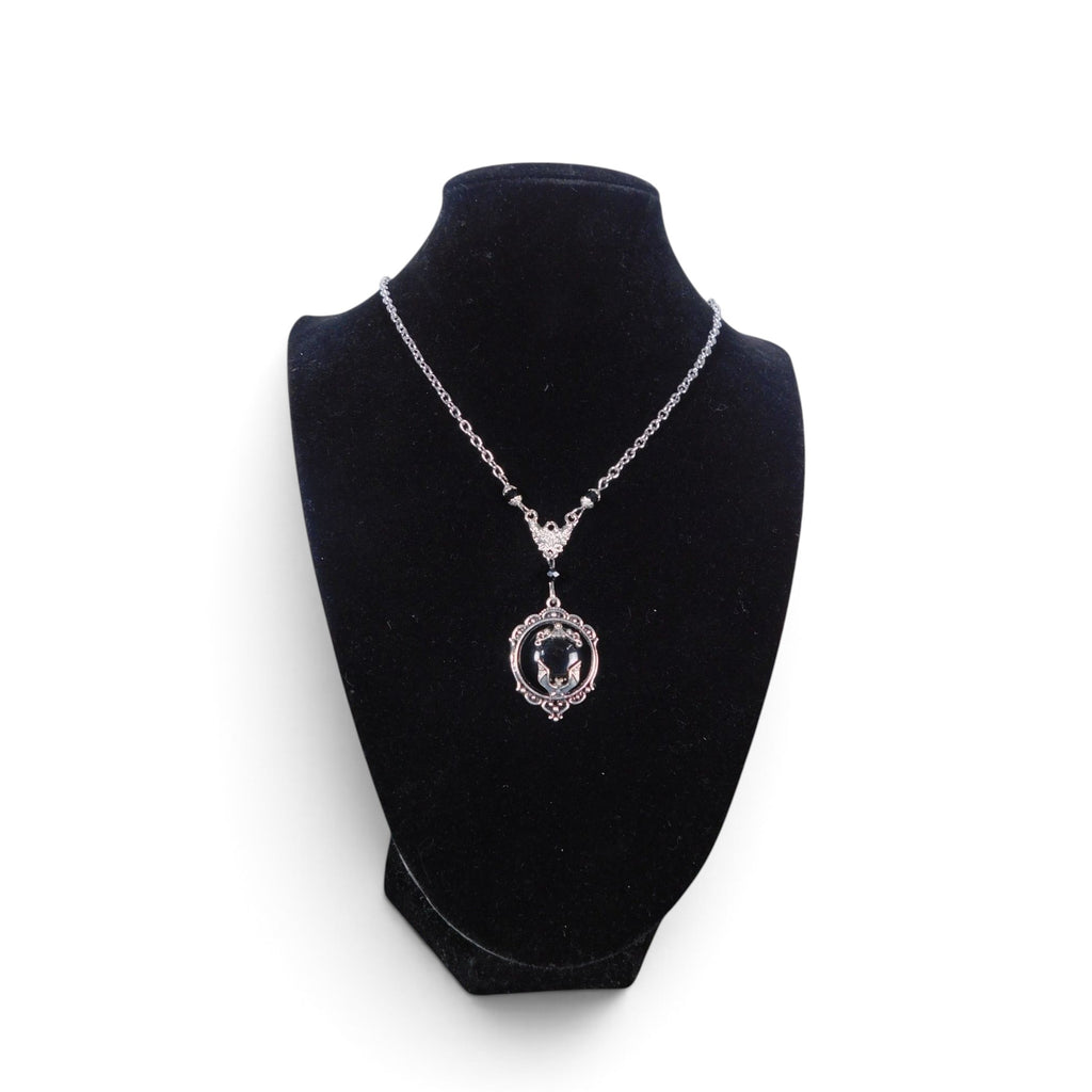 The Witches' Quest Victorian gothic bat cameo necklace in silver-tone alloy with a black resin backdrop on a display.