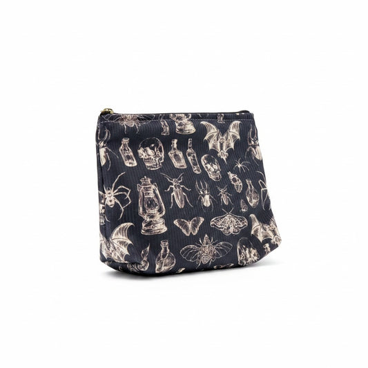 The Witches' Quest gothic makeup bag in black fabric with a white skull, insect, and lantern print and zipper closure.