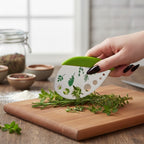 The Witches' Quest green herb mezzaluna knife with stainless steel blade and herb stem-stripping holes on wood board