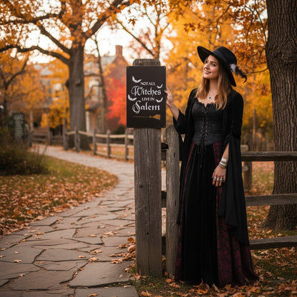 The Witches' Quest metal wall sign with Not All Witches Live In Salem text held by a woman in a witch costume outdoors