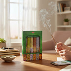 The Witches' Quest HEM Money Series incense sticks in a green box with a hand burning a stick on a wooden desk.
